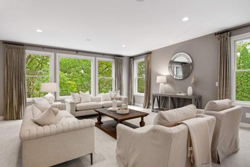 Living room off the entry surrounded by windows with treetop views