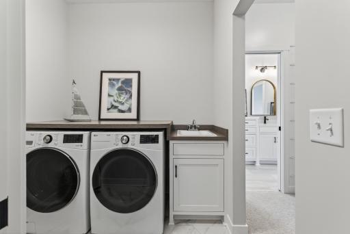 Top of the line Washer and Dryer with folding counter above and utility sink.