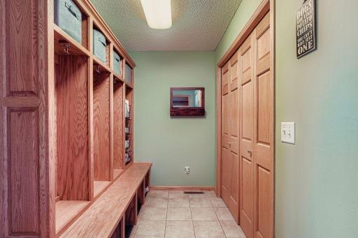 The mudroom between the kitchen and the garage features tile flooring, several cubbies and a large closet