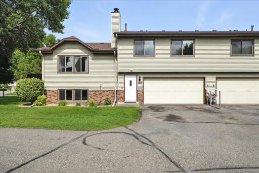 Well-maintained townhome featuring a two-car garage, vinyl siding, and charming brick accents.