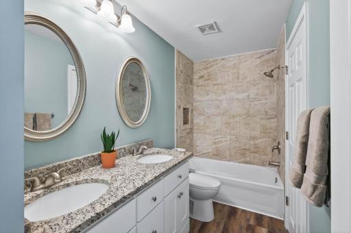 Full bath with dual sinks and tiled shower