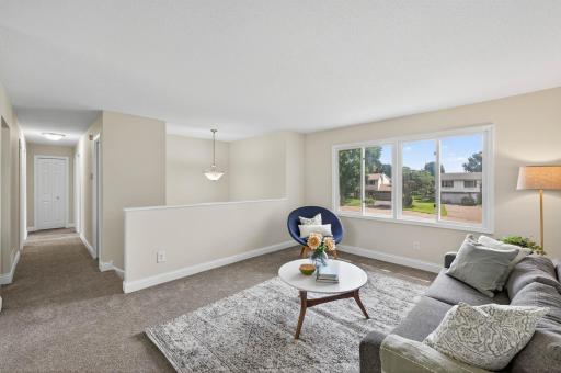 Bright open-concept living room with large windows and new carpet.