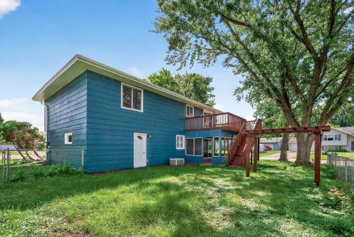 Rear exterior view of home with lush yard, screened porch, and large deck.