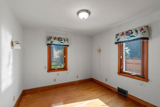 Main level bedroom with hardwood floors and double windows.