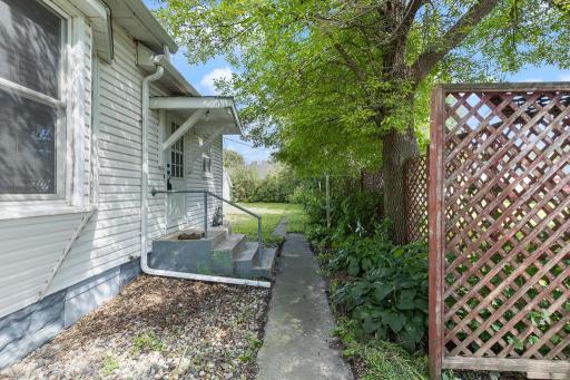 A concrete path runs behind the home to the backyard as well as a back home entry and garage access