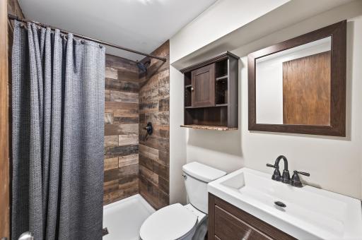 Lower level 3/4 bathroom features a stone tiled shower and updated fixtures