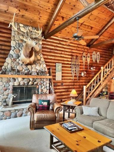 View from the great room showing the fireplace, log panel walls and stair case to the upper loft area