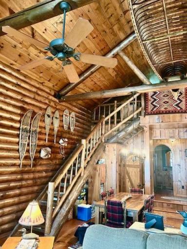 Stairs to upper level loft and showing some of exposed beams. Large main floor dining area