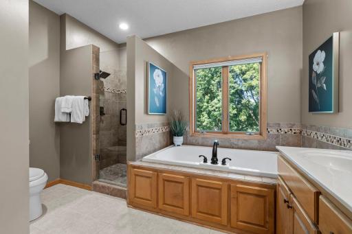 The ensuite bath enhances the spa-like experience with a tiled walk-in shower, jetted tub, dual vanity, and linen cabinet.