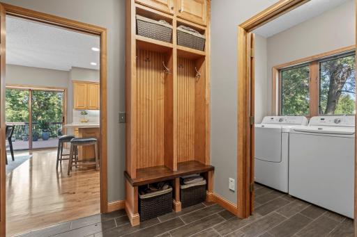 The mudroom has built-in benches and lockers, connected to the laundry room with Maytag appliances, sink, and cabinetry. The insulated three-car garage offers shelving, a workbench, and freshly painted floors.
