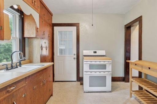 The back door is in the kitchen. It has a double oven electric range. The refrigerator is located in an adjacent niche.