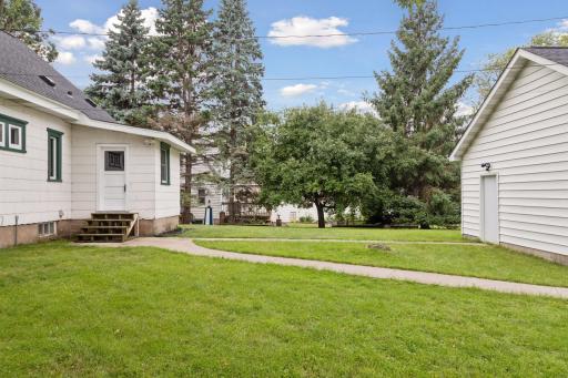 A cement sidewalks connect the house to the large garage and the driveway.