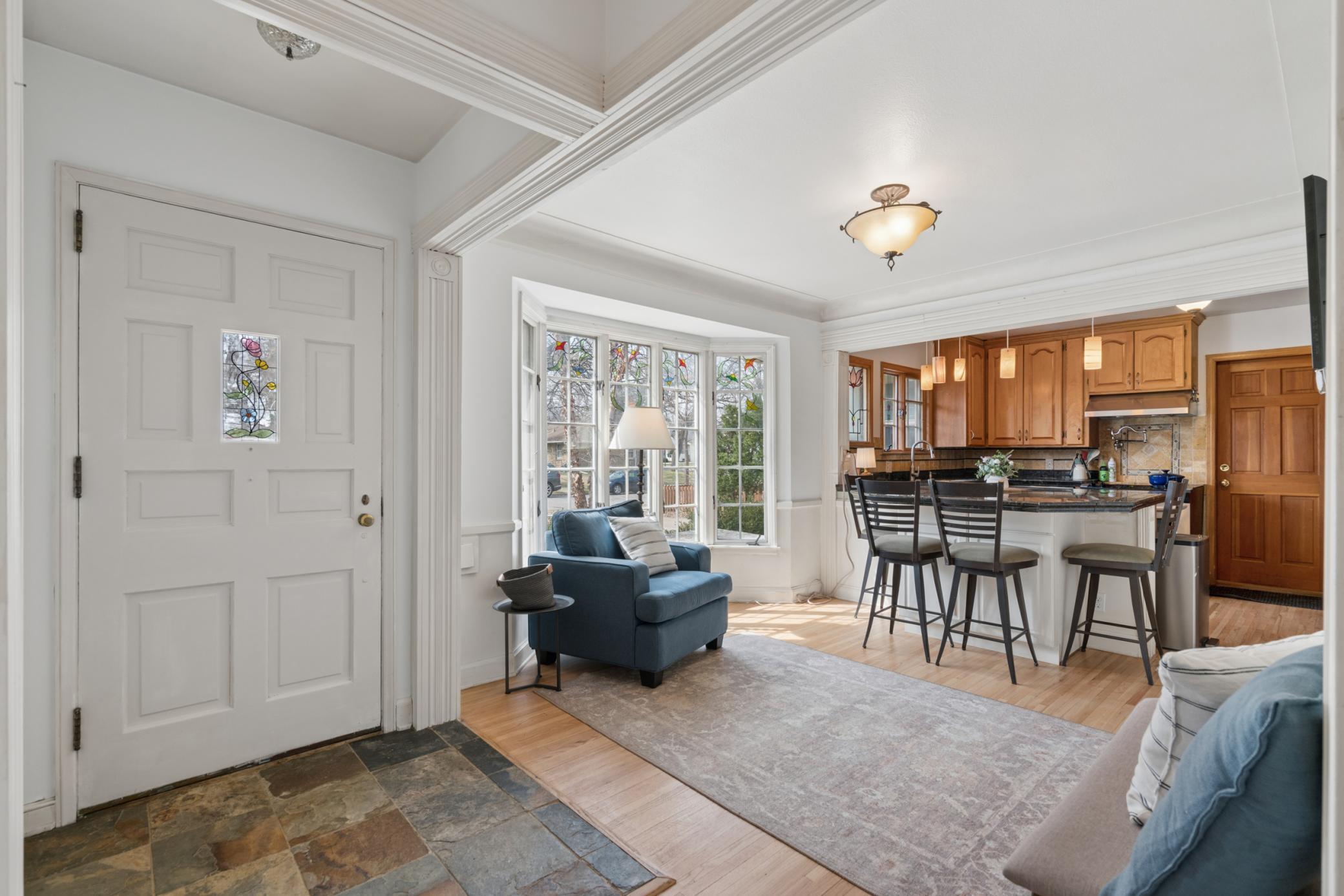 Welcoming front entry with charming architectural details, abundant natural light, and a flexible sitting area that connects to the kitchen.
