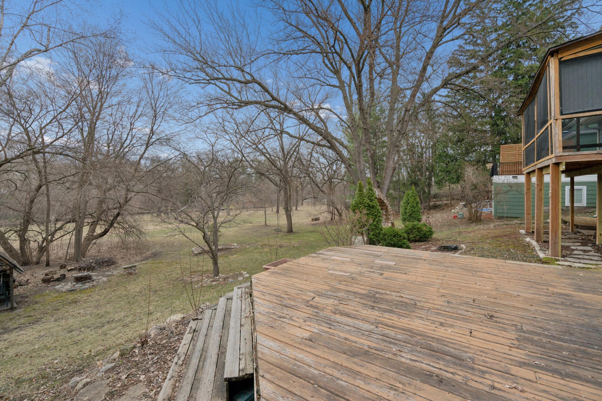 Expansive deck overlooking a rare, park-like backyard with direct views of Minnehaha Creek and protected park board land