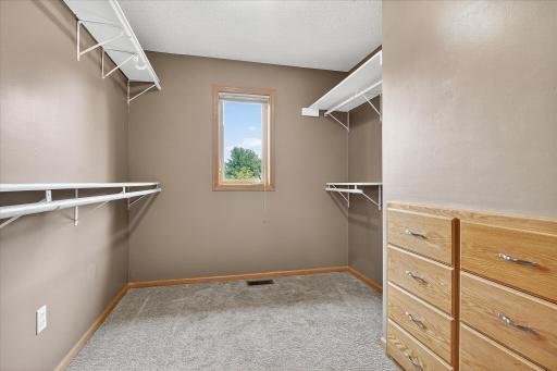 The walk-in closet has upgraded carpet, upper & lower hanging rods & shelves, a window, and a built-in dresser.