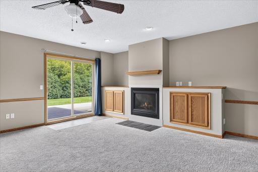 The lower level Family Room features modern & neutral paint & carpet, a ceiling fan, a gas fireplace and storage cabinetry.