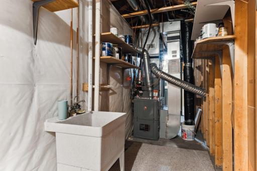 The furnace room has a utility sink and an updated furnace, which was installed in 2019, along with the AC & thermostat.