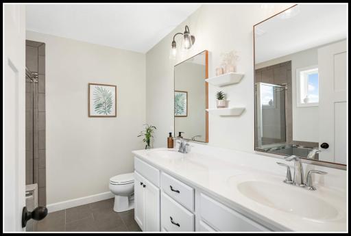 Tastefully updated primary bathroom features a double-sink vanity . . .