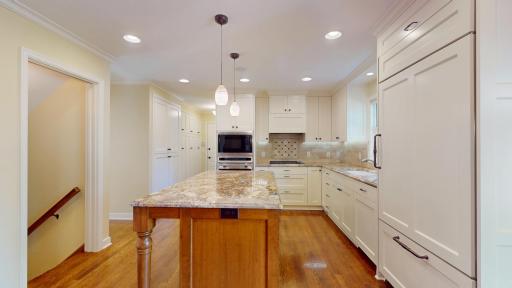 Stunning updated kitchen with sleek enamel finishes, granite surfaces, and a large center island that doubles as a workstation and casual dining bar.