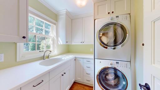 Main floor laundry made easy with Electrolux washer & dryer, sink, built-in ironing board and plenty of storage