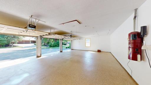 Expansive three-car garage with epoxy-finished floors and two pedestrian, front & back side doors for convenient everyday practicality