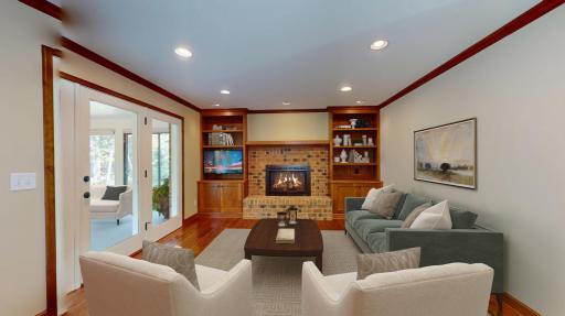 Family room off the kitchen with gas fireplace, built-ins and TV. virtually staged