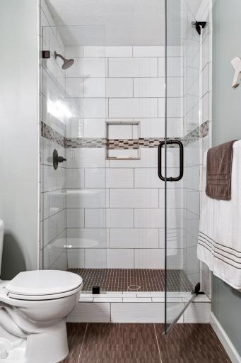 Beautiful tile work and handsome frameless glass shower door.