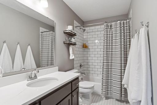 Upper level hall bath boasts handsome subway surround, flooring and solid surface vanity.