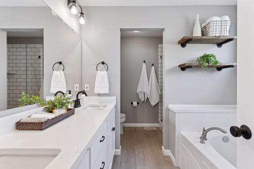 Owner's bath with large soaking tub, dual sink vanity with newer quartz countertops and large walk-in tile shower.