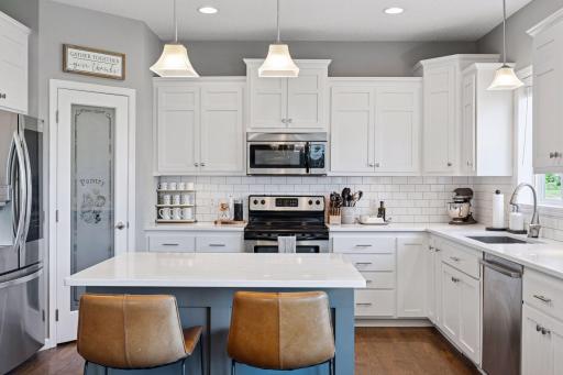 Handy snack bar at kitchen island. Also note newer upgraded fridge, dishwasher and gorgeous quartz counters with under mount sink.
