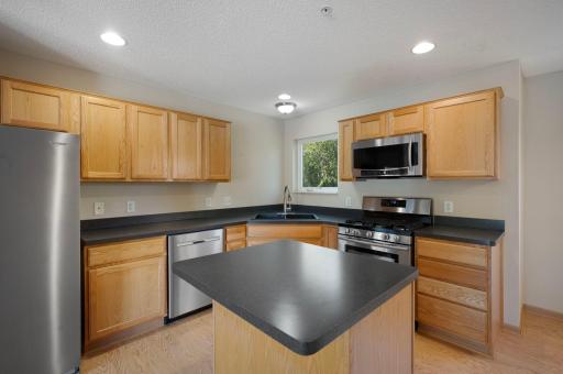 Kitchen features stainless steel appliances and kitchen window overlooking the backyard green space.