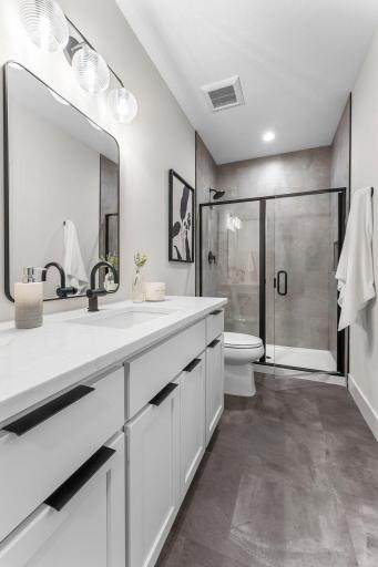 It is connected to a walk-through Â¾ bath with a tile walk-in shower, single vanity, and linen cabinetâperfect for guests or family.