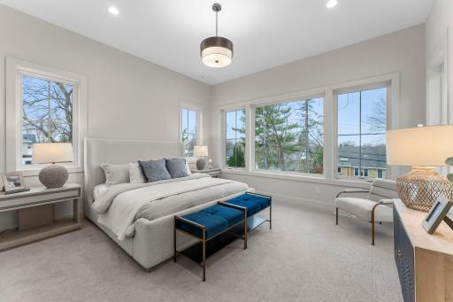 Upstairs, the primary bedroom is a private retreat, entered through elegant French doors. It is filled with natural light from oversized windows.