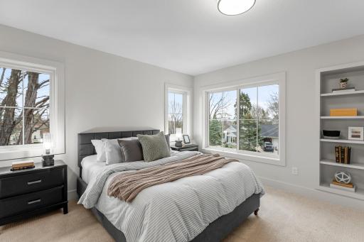 Across the hall, a fourth bedroom includes built-in wall shelving for decor or storage, along with cohesive carpeting and a 5 by 6 walk-in closet.