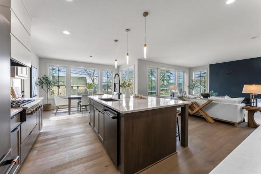 The open concept flows seamlessly into a sun-filled dining area with large picture windows and statement lighting.
