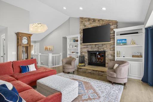 The living room features soaring 13-foot vaulted ceilings, expansive windows, and a cozy wood-burning fireplace, creating a warm, inviting atmosphere.