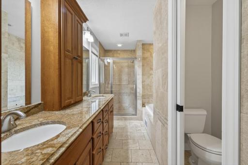 The primary bedroom includes a full ensuite bath with walk-in tiled shower, dual vanities, and ample closet space.