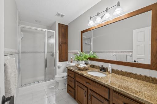 A well-appointed three-quarter bathroom features a walk-in shower, modern fixtures, and convenient access from all lower-level rooms.