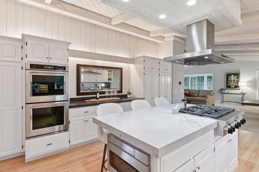 Center island with quartz countertop, gas cooktop, and vent hood.