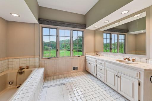 Double sinks, vanities, tile flooring, and large windows.