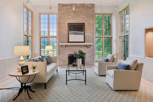 Light-filled living room with floor-to-ceiling windows, serene wetland views, and a cozy wood-burning fireplace