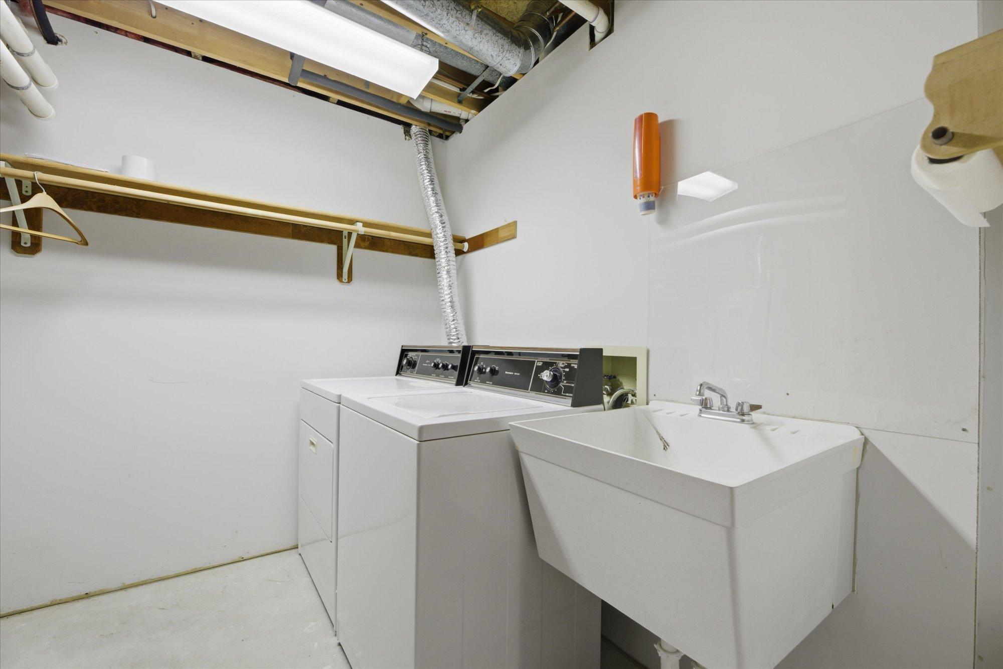 Lower-level laundry/mechanical room with washer/dryer hookup, utility sink, additional storage and hang for clothing.