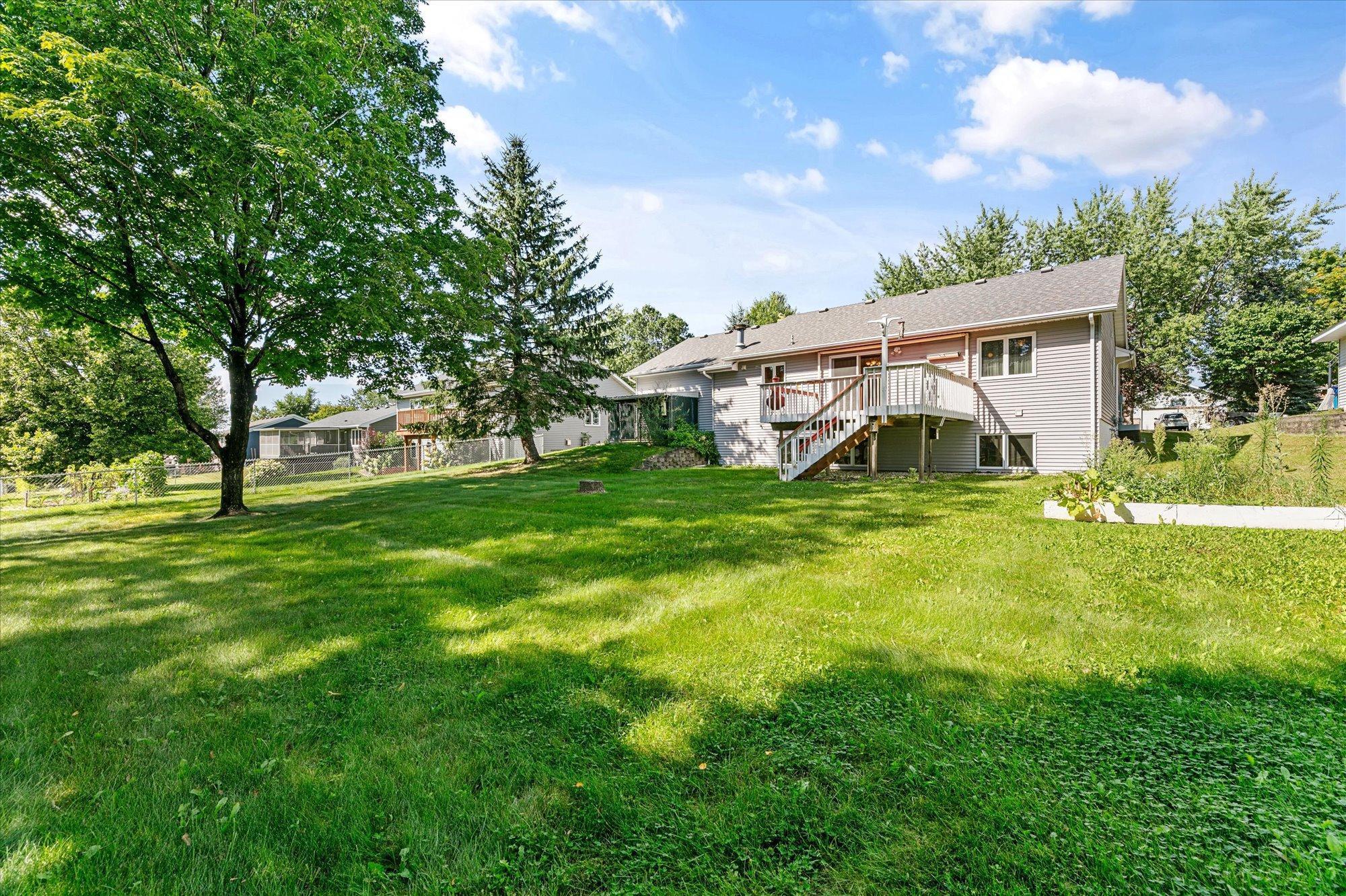 Large backyard with lush grass and mature trees.