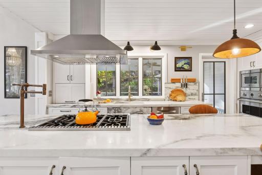 Striking marble island with professional-grade range, statement hood, and sunlit prep space