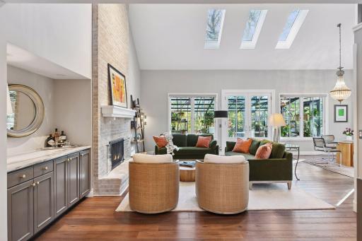 Sun-drenched great room with soaring ceilings, skylights, and French doors opening to the conservatory