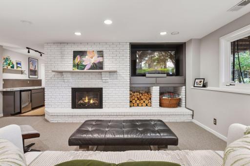 Inviting lower-level family room with fireplace, built-ins, and adjacent bar area for entertaining