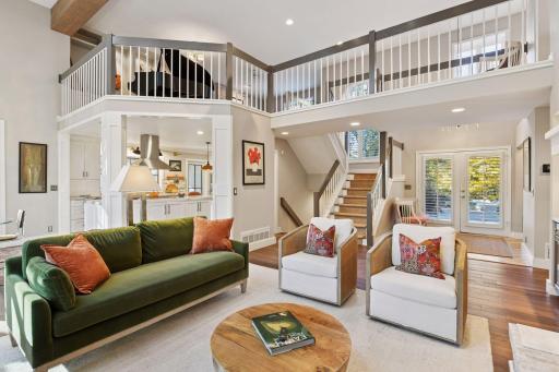 Dramatic two-story living area with open loft, sunlit stairway, and seamless flow to the kitchen