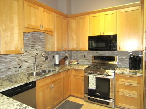 Remodeled kitchen with tiled back splash, granite counters and stainless steel appliances.