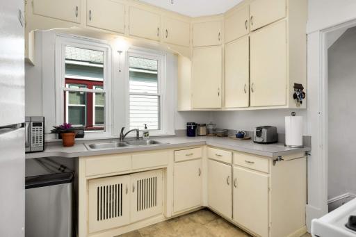 The kitchen is filled with period charm, such as the louvered doors below the sink and decorative flourishes under the top cabinets.
