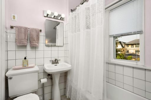 The charming bathroom has a vintage feel, with a newer tile floor, sink and commode.